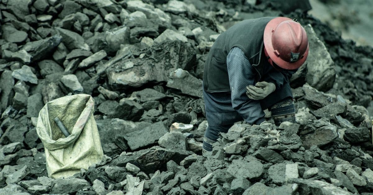 A woman mining for gold in La Rinconada, Peru, surrounded by rocks and debris.
