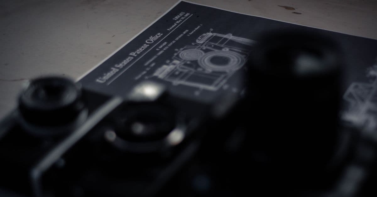High angle collection of professional retro photo and film cameras arranged on table with patent document