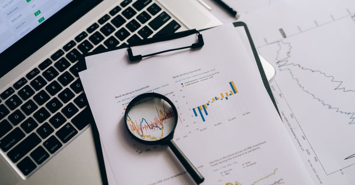 Overhead view of financial charts, laptop, and magnifying glass, ideal for business analysis themes.