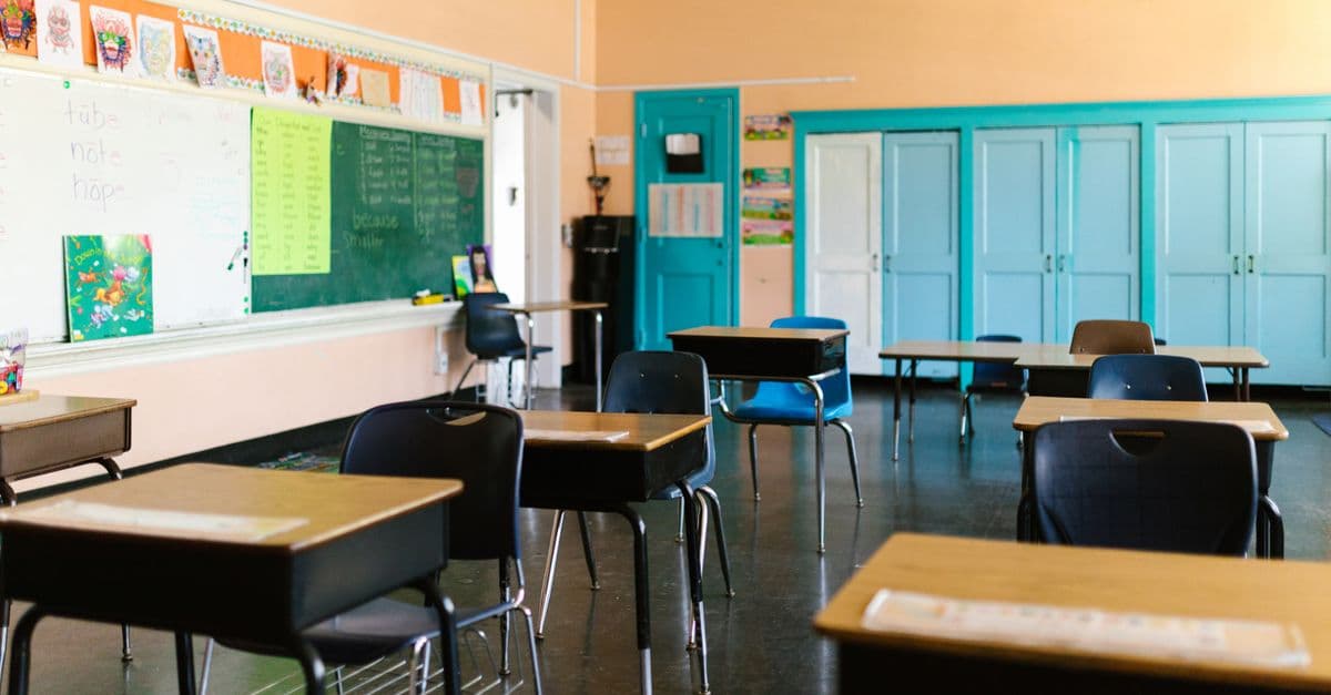 Bright and colorful empty classroom with desks, blackboard, and educational materials.