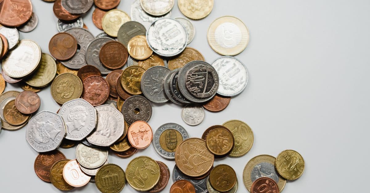 A collection of various international coins spread on a soft white background.
