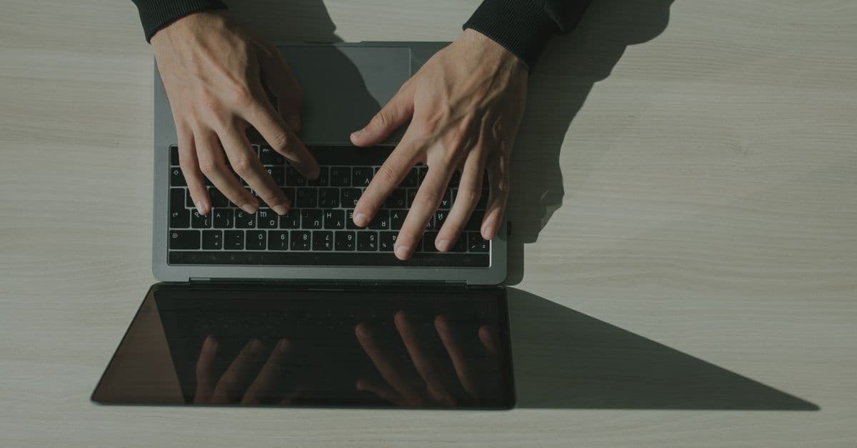 Overhead shot of hands typing on a laptop, showcasing technology and internet usage.