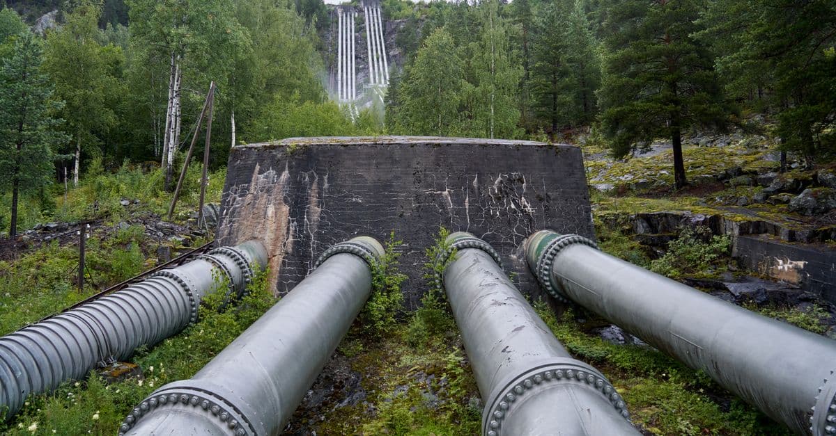 Hydroelectric plant pipes amidst lush greenery in Rødberg, Norway.