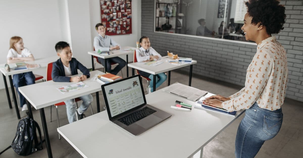 Teacher interacting with students in a modern classroom setting, fostering education.