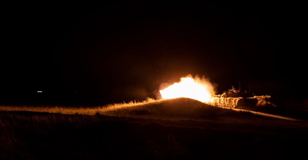 A powerful fireball eruption during nighttime military training creates a dramatic scene.