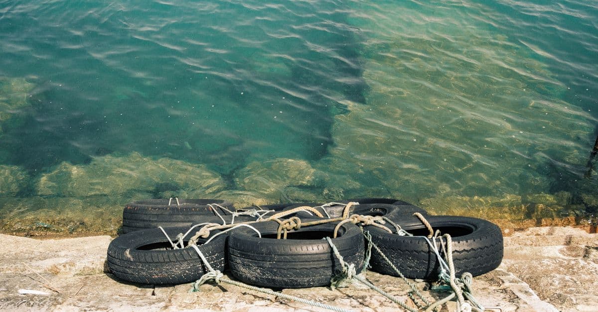 Close-up of tires tied on a dock by the sea in Lagos, Portugal, under bright sunlight.