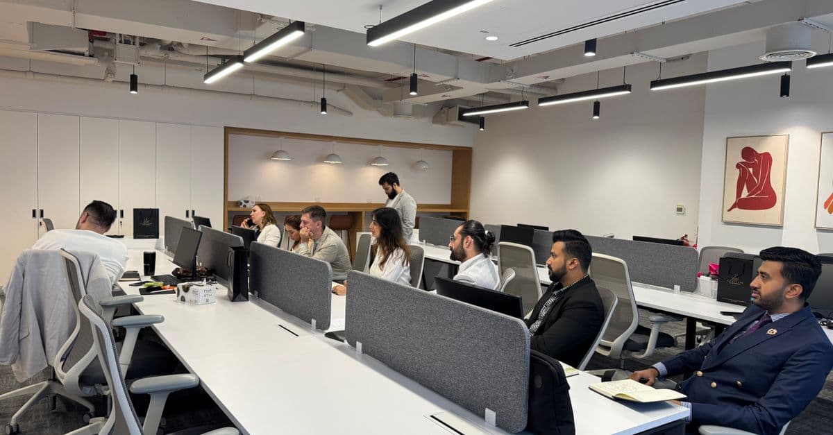 Diverse team working in a modern office setting with computers and collaborative spaces.