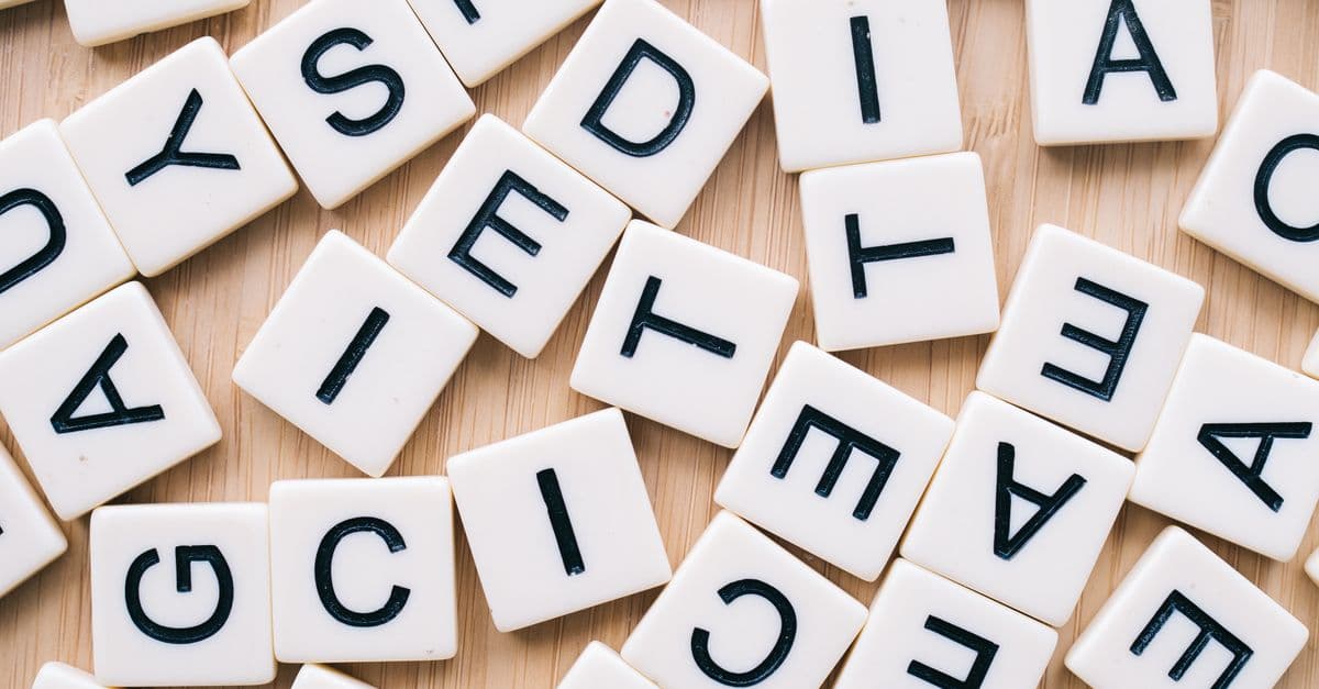 Closeup of scattered scrabble tiles against a wooden background, ideal for word games and learning themes.