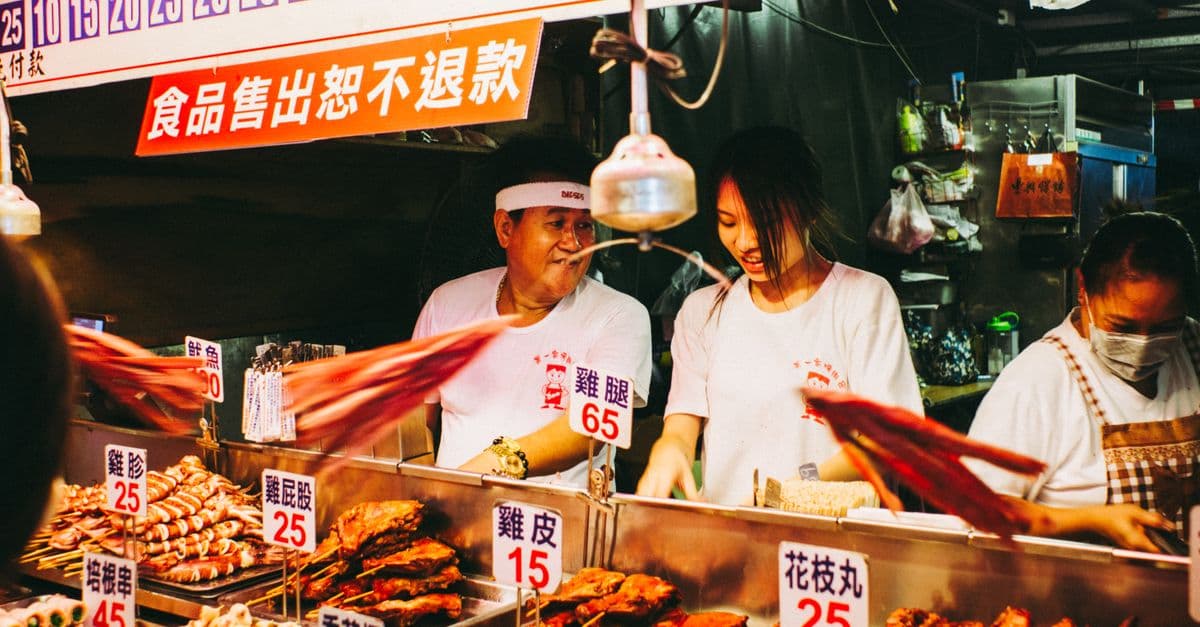 Vibrant scene at a bustling Taiwanese night market food stall with vendors.