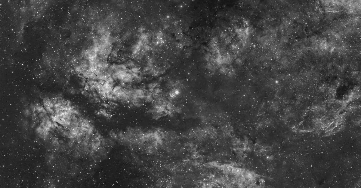 Black and white image capturing a detailed view of the starry sky with cosmic clouds.