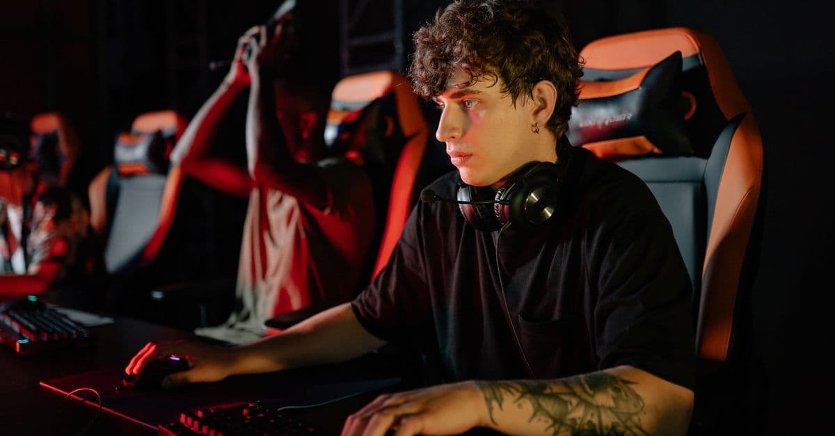 Competitive gamers in an esports tournament concentrating deeply in dimly lit setting.
