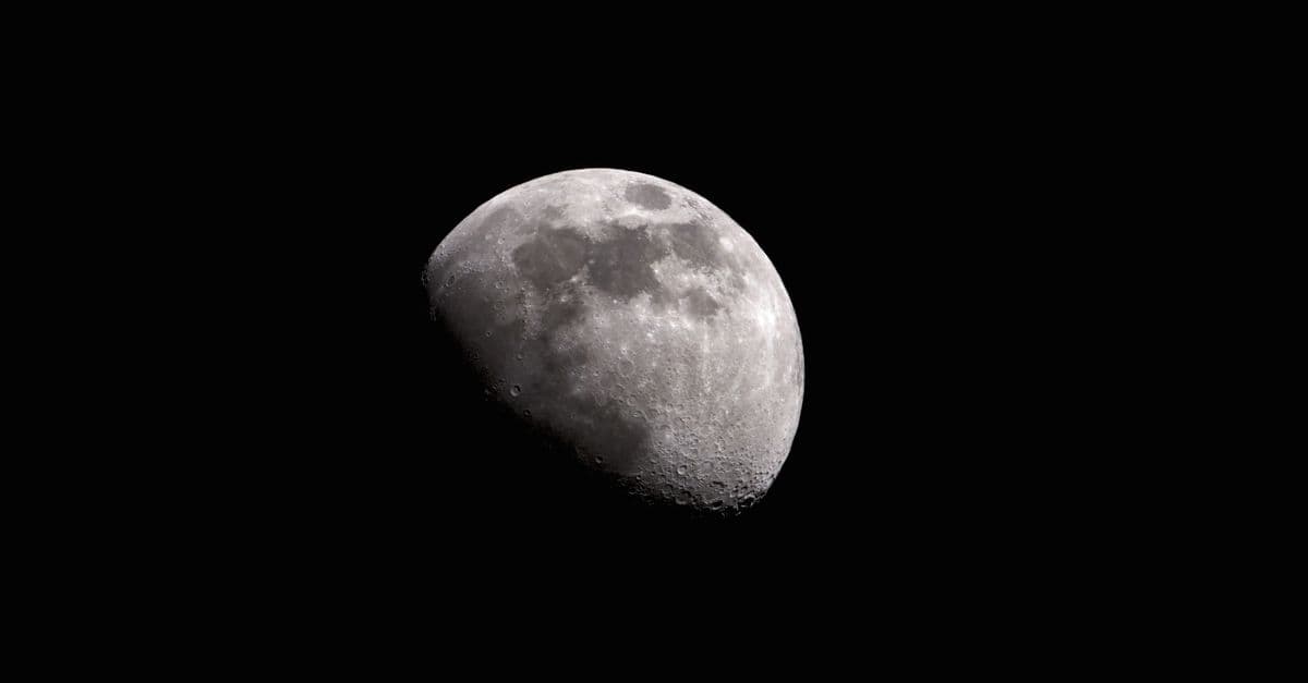 Black and white of moon with craters glowing on black sky at night