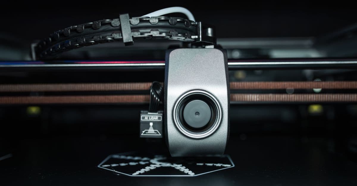 Detailed close-up of a 3D printer extrusion head in focus, showcasing modern technology.