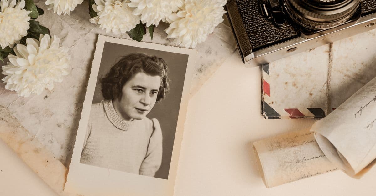 A nostalgic composition featuring a vintage photograph, old camera, and white flowers.