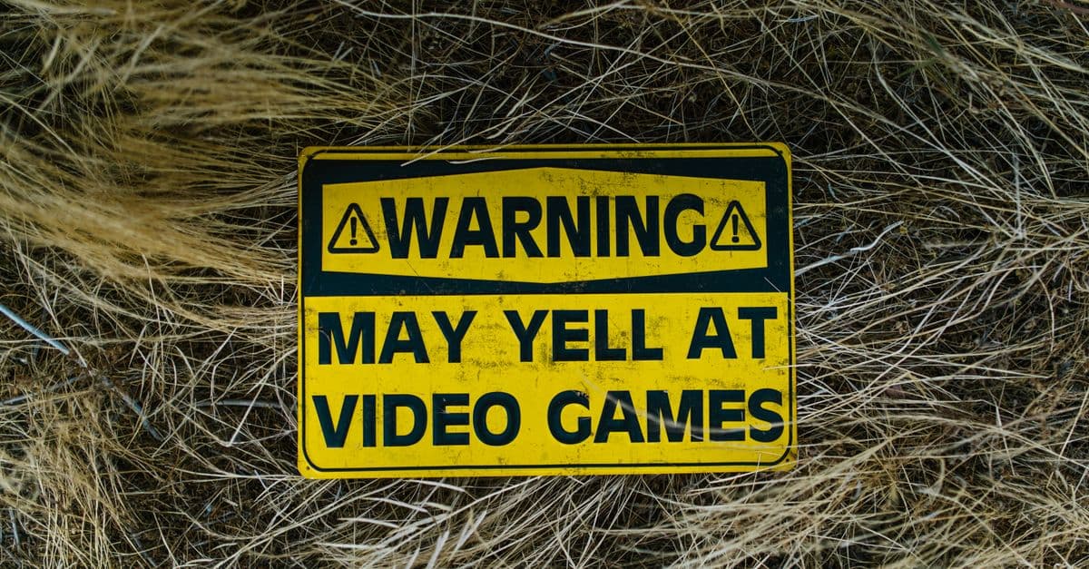 A funny yellow warning sign on grass reading 'Warning May Yell at Video Games'.