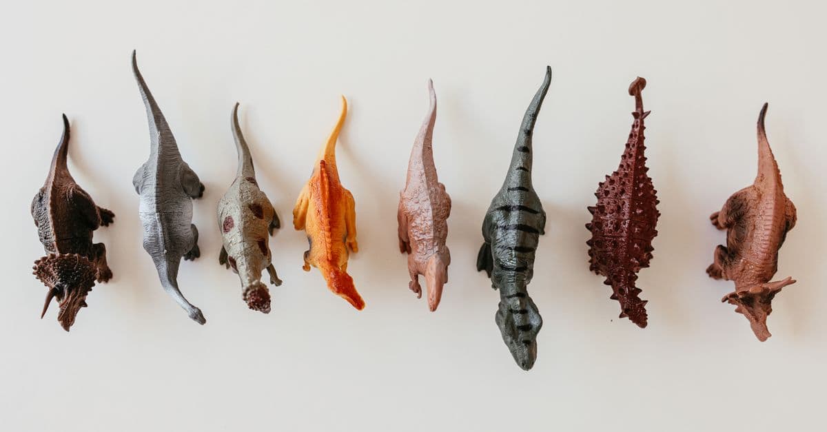 Top view of dinosaur toy figurines arranged on a white background, ideal for educational or play scenes.
