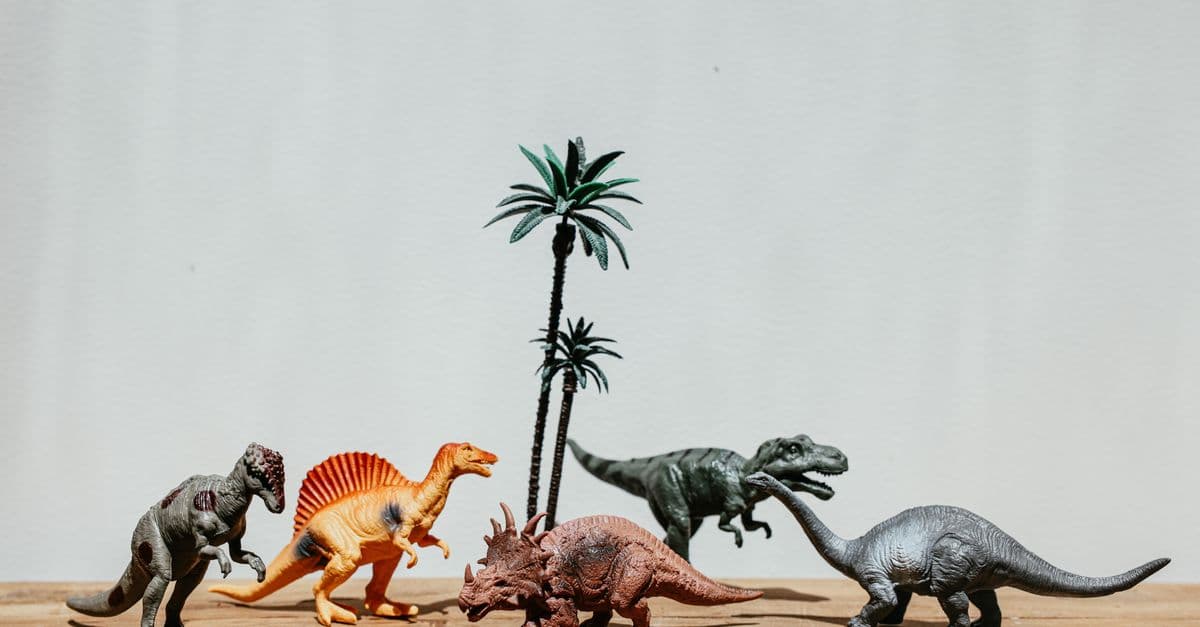 A variety of dinosaur toy figurines displayed on a wooden table under soft lighting.