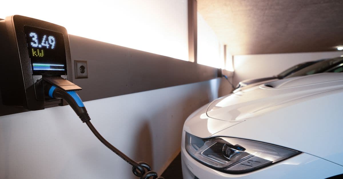 White electric car charging at indoor station, emphasizing sustainability and efficiency.
