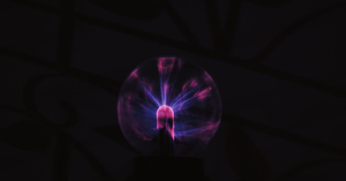 From below of glowing plasma ball with neon light placed in dark room