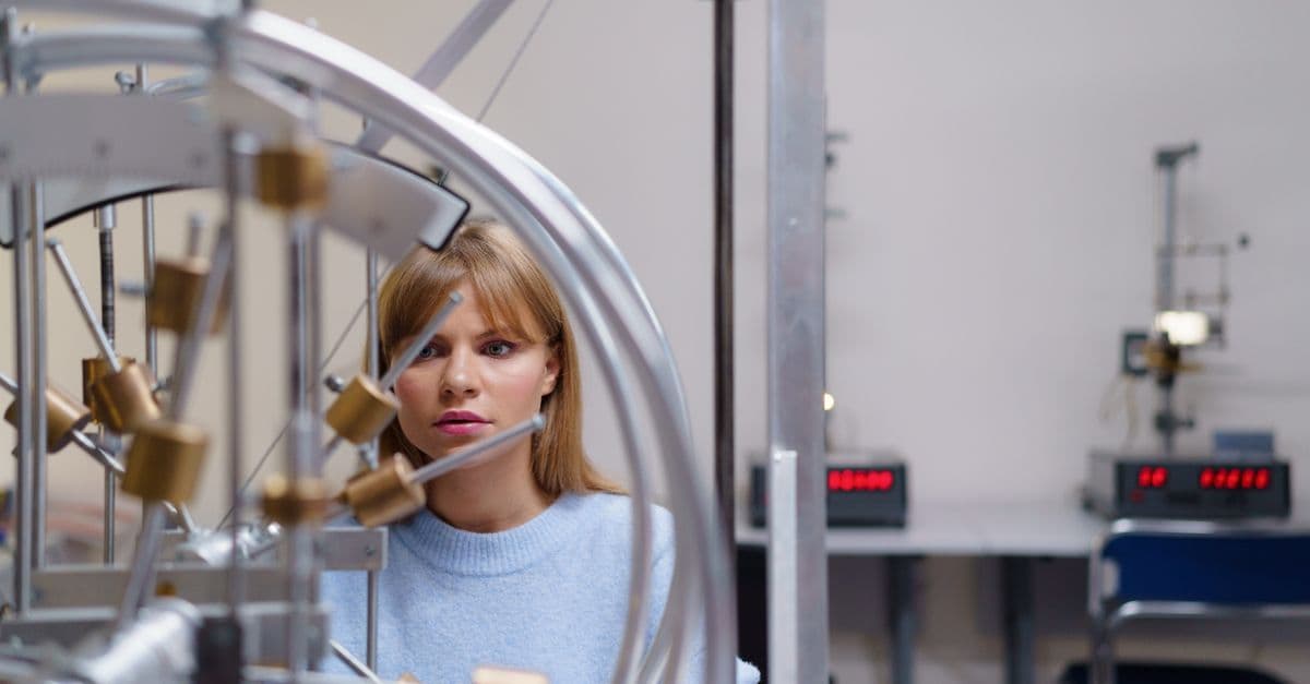 Focused student engaging with physics equipment in a university lab setting, illustrating interactive learning.