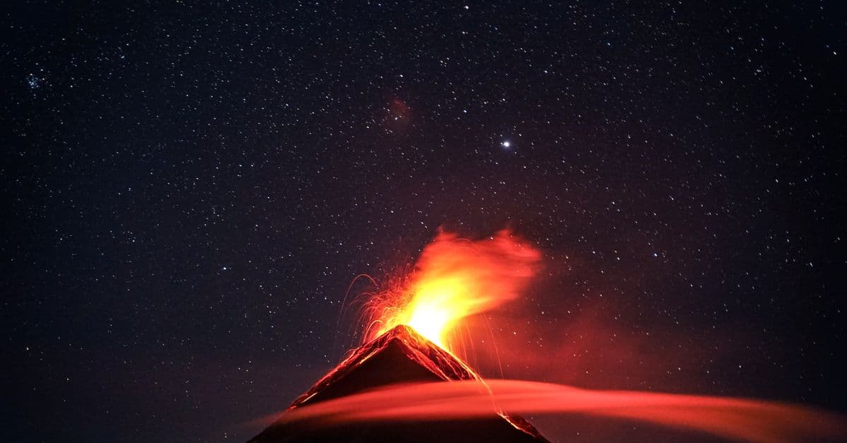 A dramatic volcano eruption in Guatemala beneath a star-filled night sky, showcasing nature's power.