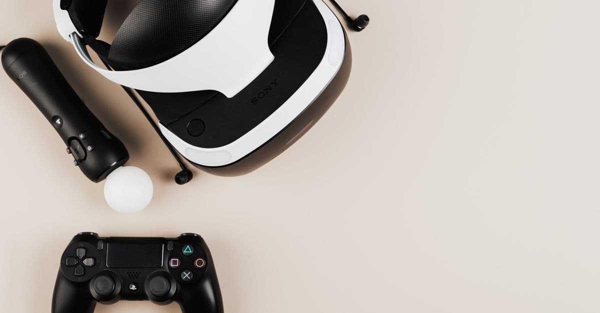 High-angle view of gaming controllers and VR headset on beige surface, showcasing modern technology.
