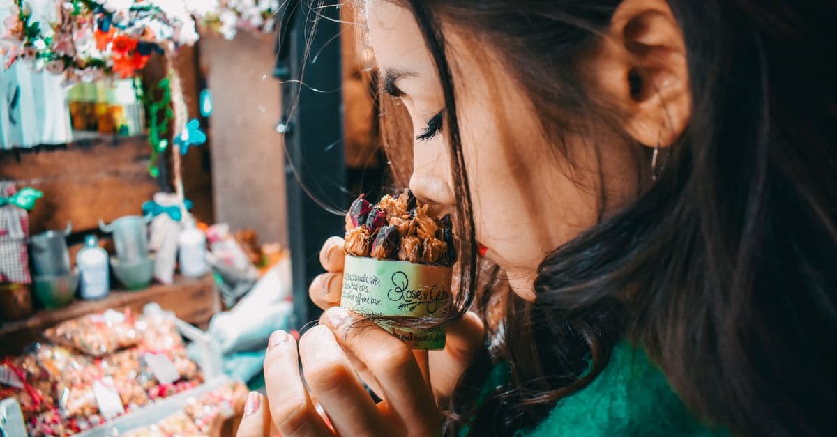 A woman savoring the scent of potpourri at a vibrant London market, capturing the essence of street life.