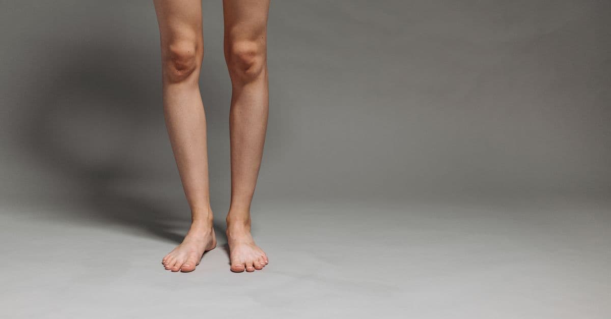 Studio shot of a person's lower legs and feet on a gray background.