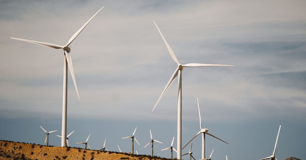 A large wind farm with turbines on a desert hill under a clear sky.