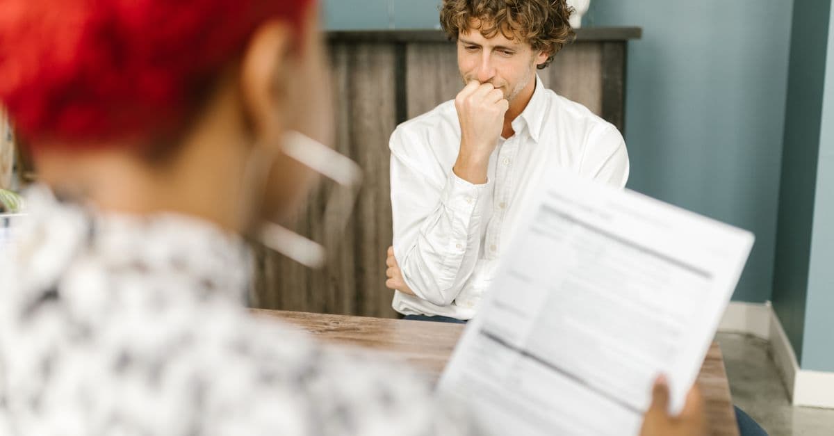 Man reflecting during a job interview in an office setting, highlighting thoughtfulness.