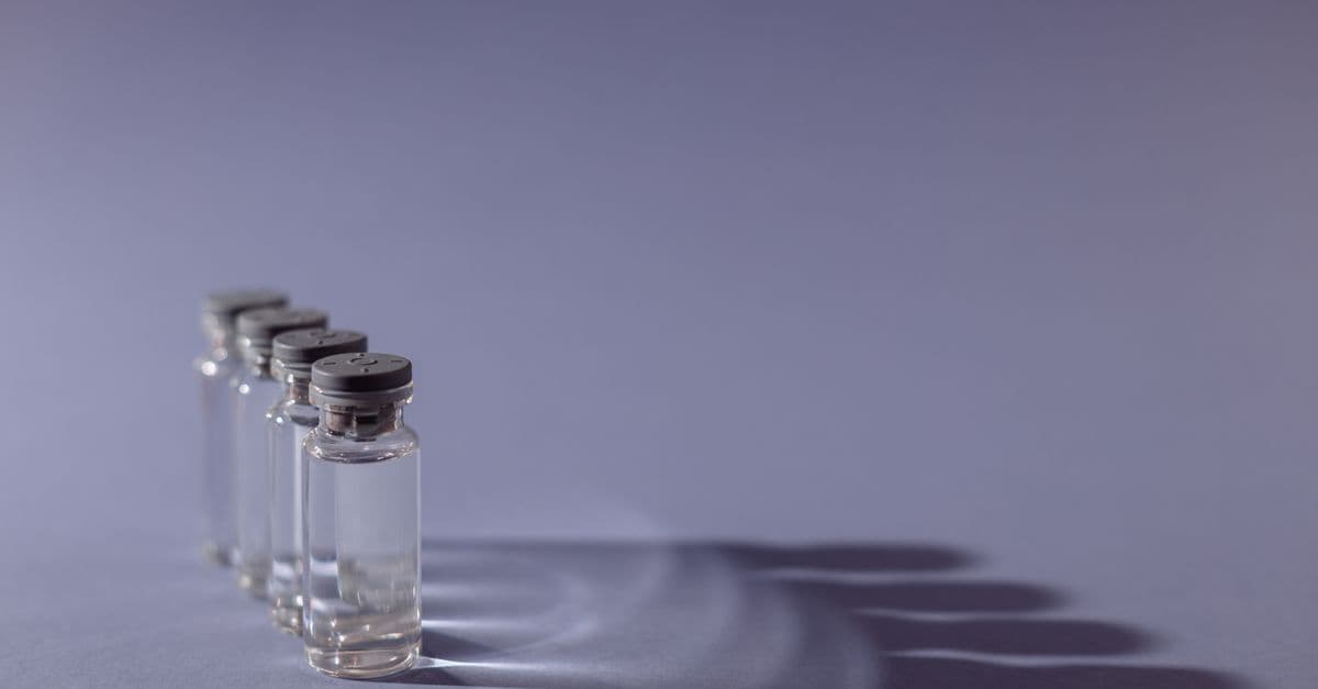 Close-up of lined up vaccine vials casting shadows, symbolizing medical advancements and health.