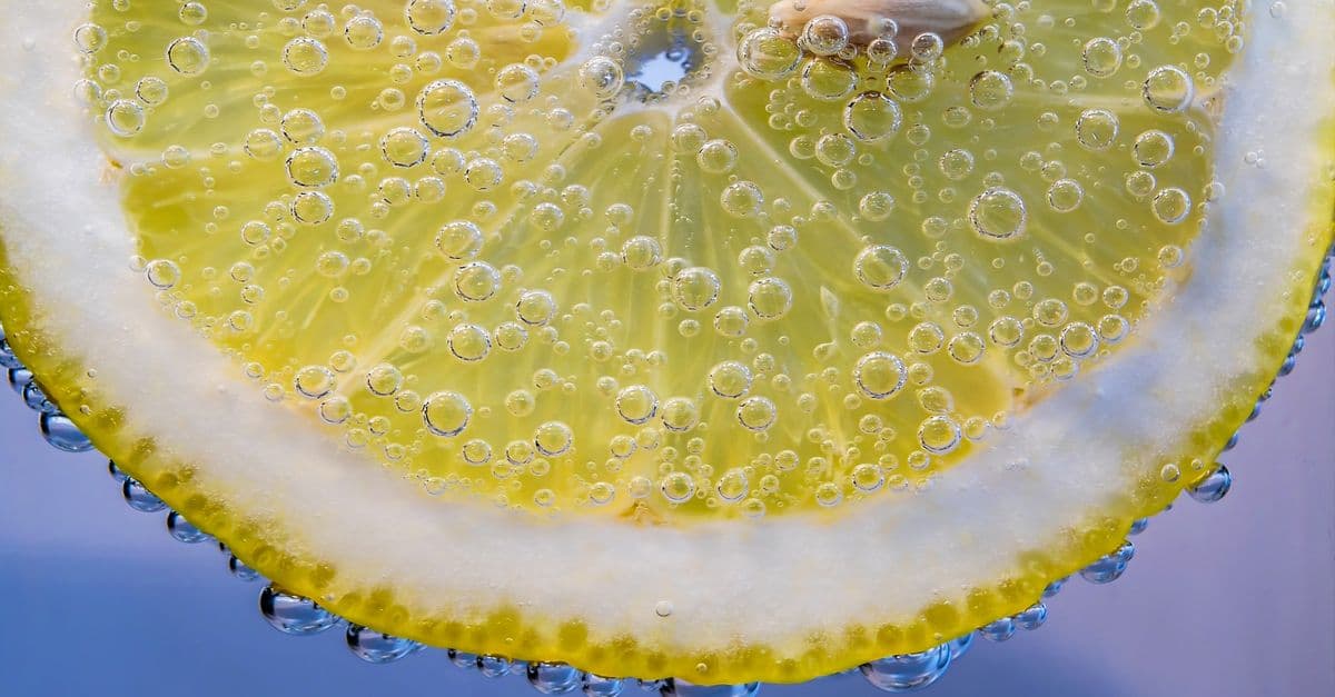 Close-up of a lemon slice submerged in water with bubbles on the surface. Refreshing and vibrant citrus imagery.