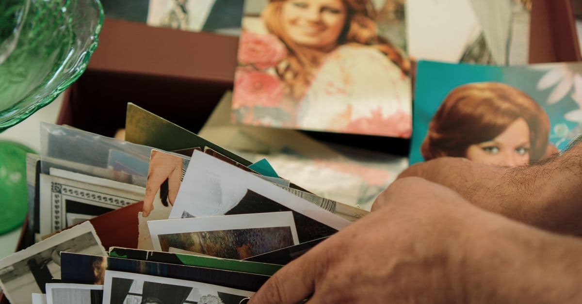 Close-up of hands sorting through a collection of vintage family photos.