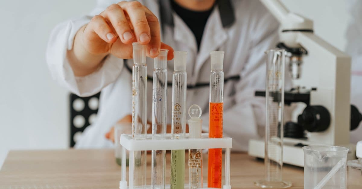 Scientist in lab coat conducting an experiment with test tubes and a microscope.