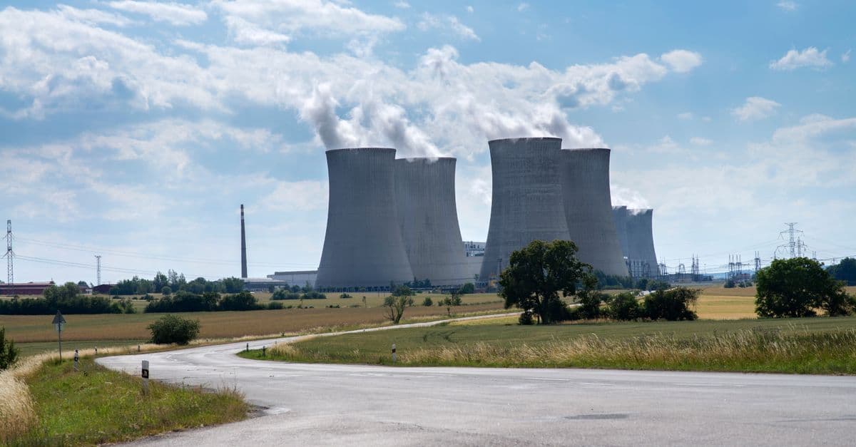 Cooling towers of Dukovany Nuclear Power Plant on a sunny day with smoke rising.
