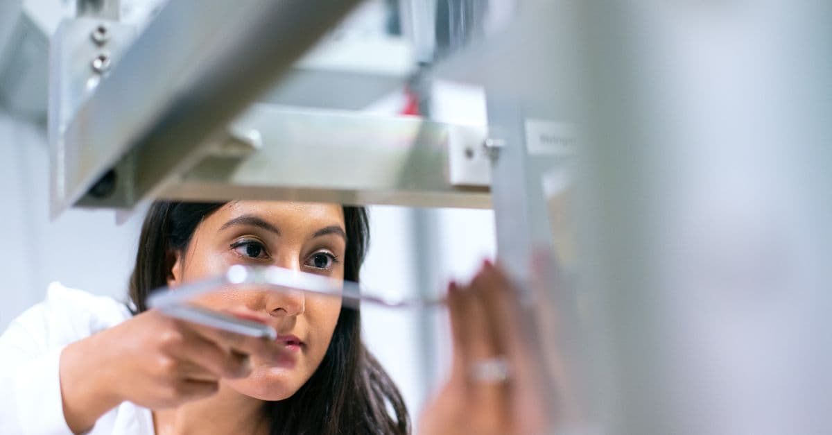 Female engineer focused on equipment in a modern lab, showcasing technology and expertise.