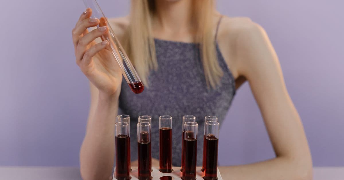 A woman in a lab handling red liquid in test tubes, showcasing scientific research.