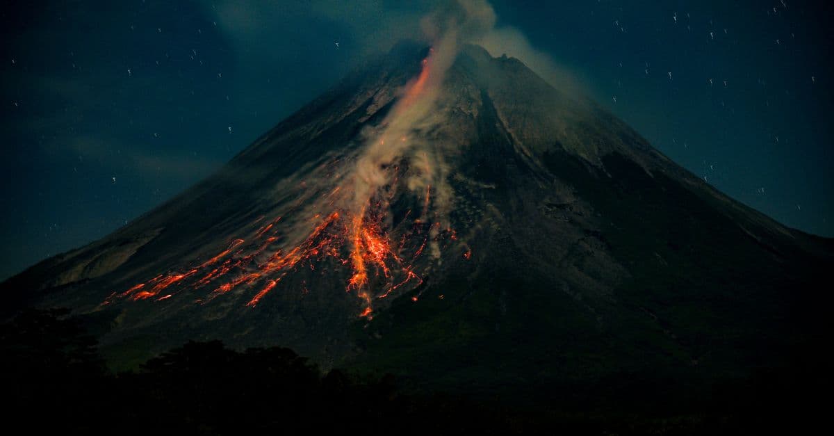 Spectacular nighttime view of a volcanic eruption in Central Java, Indonesia, with flowing lava and smoke.