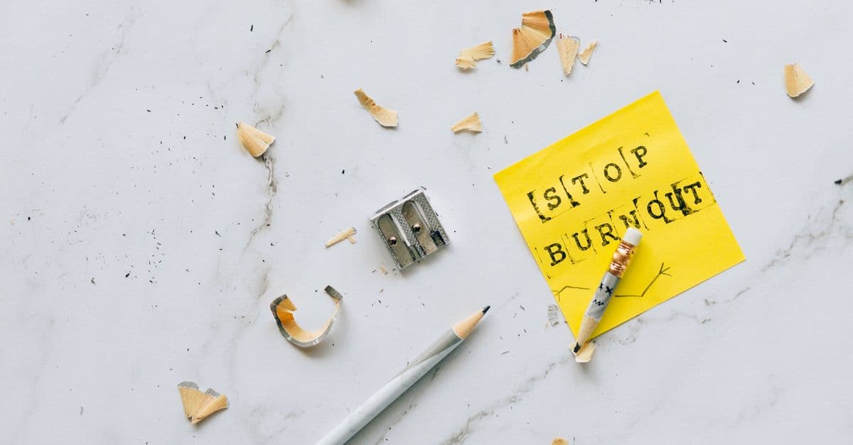 Overhead shot of a note saying 'Stop Burnout' on a marble surface with pencil shavings.