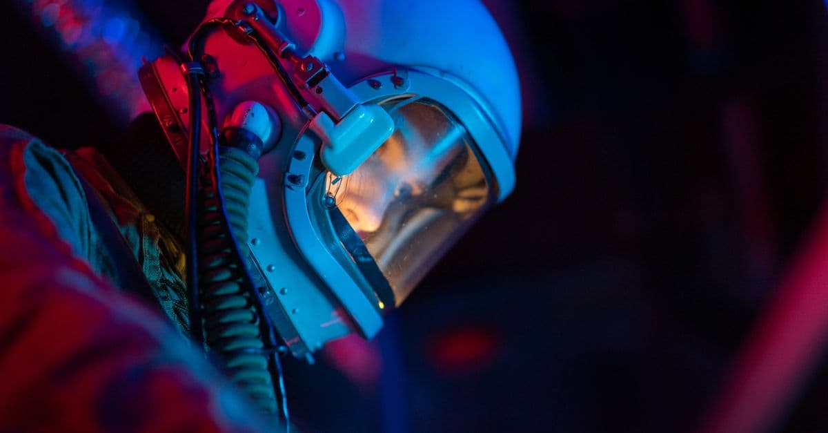 A spacewoman in a high-tech suit with illuminated helmet against a dark, futuristic backdrop.