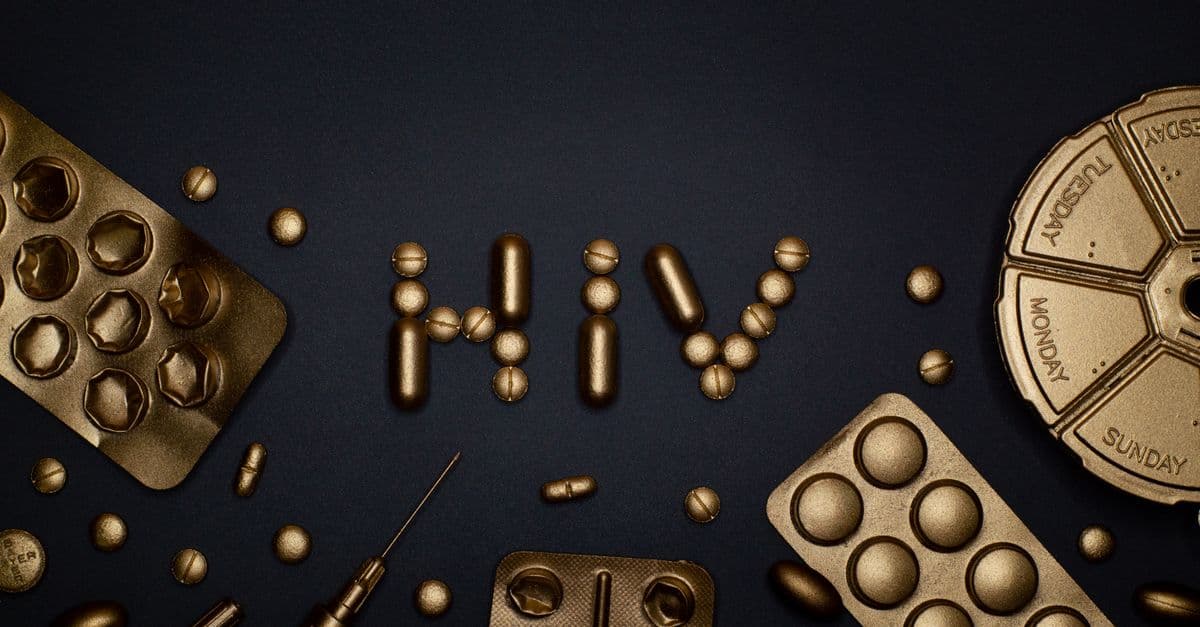 Artistic depiction of HIV with golden pills and syringes on dark background.