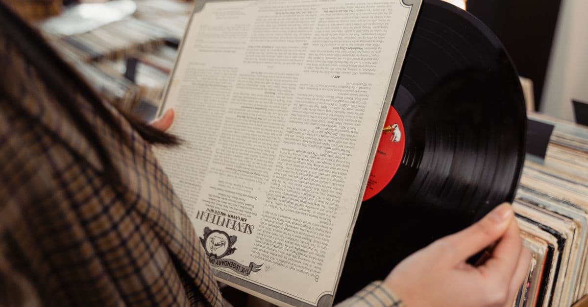 Close-up of a person holding and browsing vinyl records in a nostalgic music store.