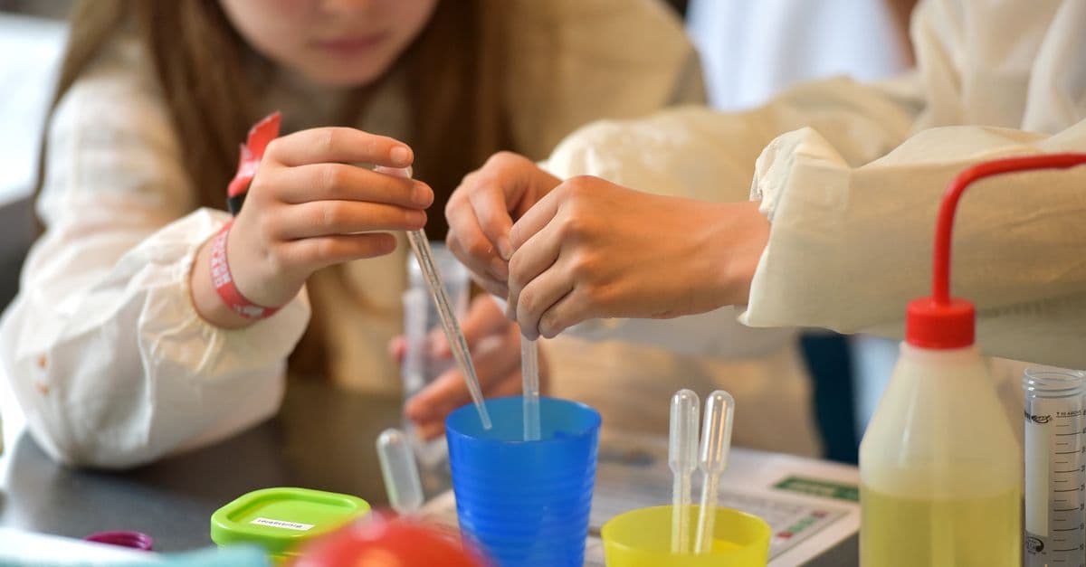 Children conducting science experiments with pipettes and safety glasses in a lab setting.