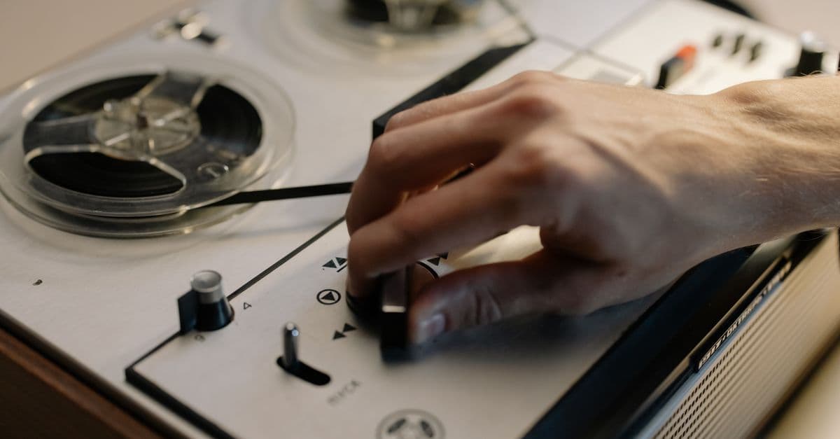 A detailed close-up of a hand adjusting controls on a vintage reel-to-reel tape recorder.
