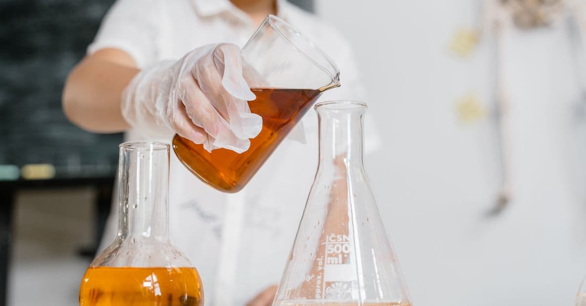 Scientist performing an experiment by pouring liquid into a flask.