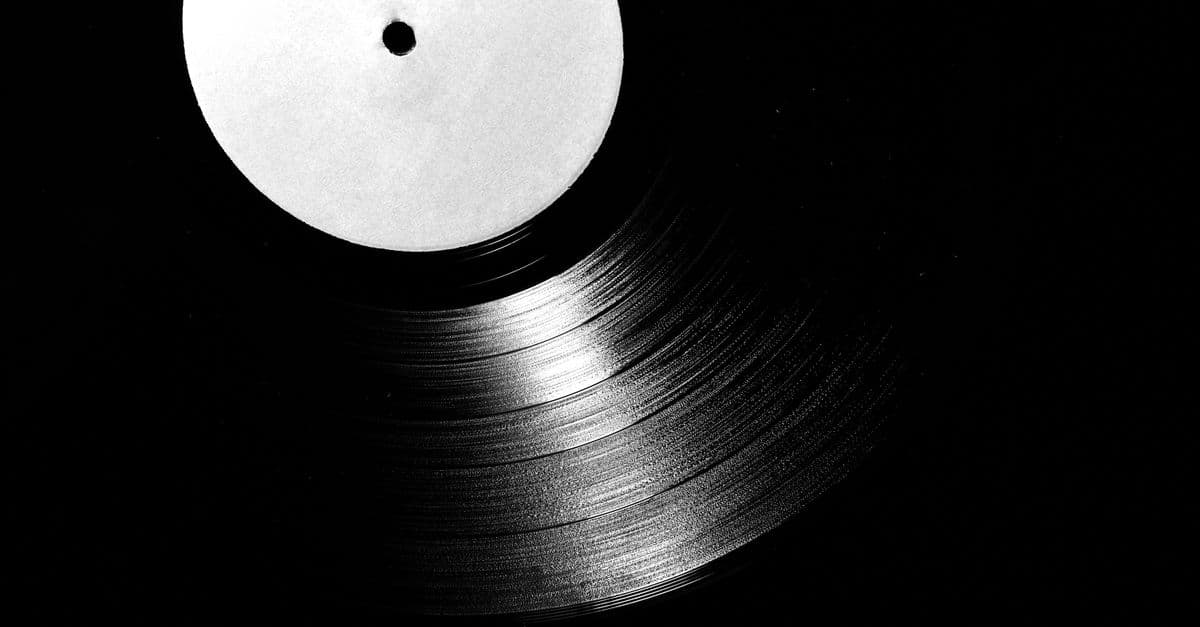 A close-up of a vintage vinyl record in black and white, emphasizing its grooves.