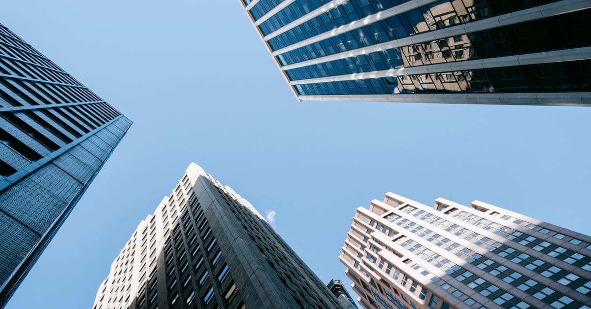 Low angle of high business center with glass mirrored windows near concrete office towers in downtown