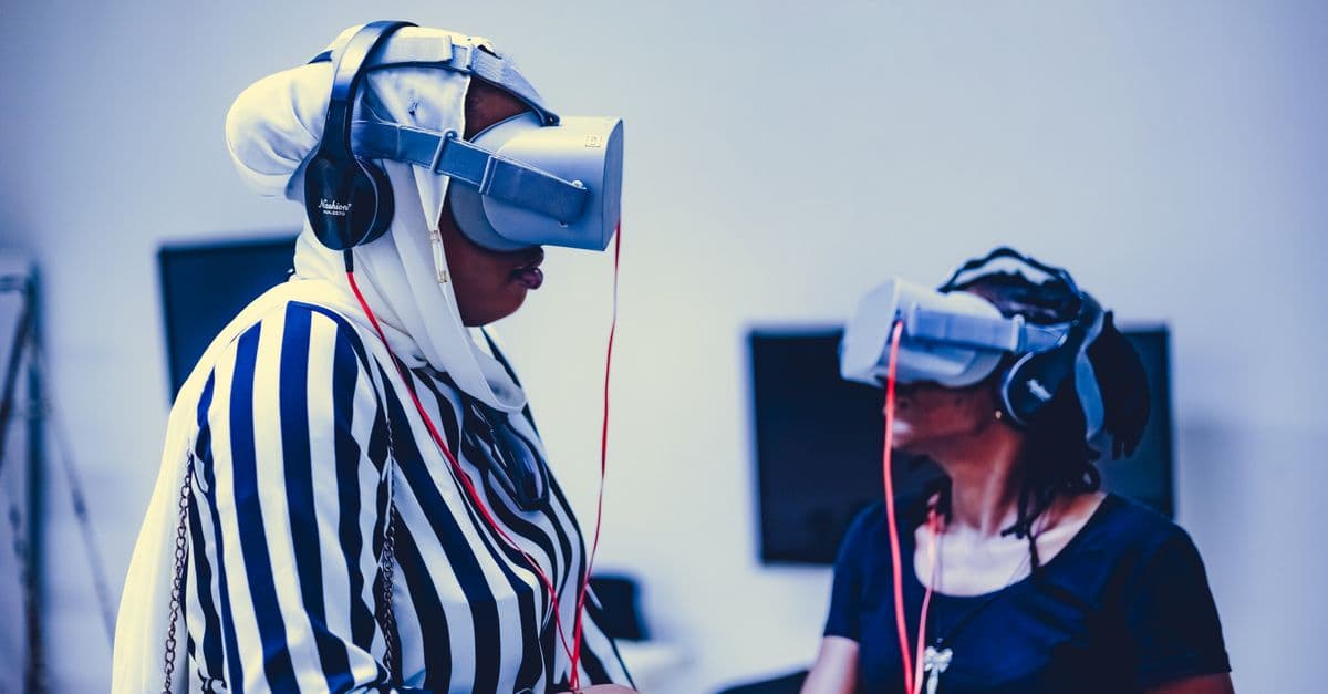 Two women using virtual reality headsets indoors, exploring immersive technology.