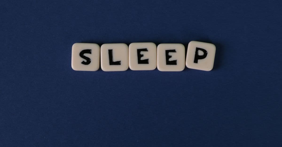 White letter tiles spelling 'SLEEP' against a dark navy background, highlighting simplicity and rest.