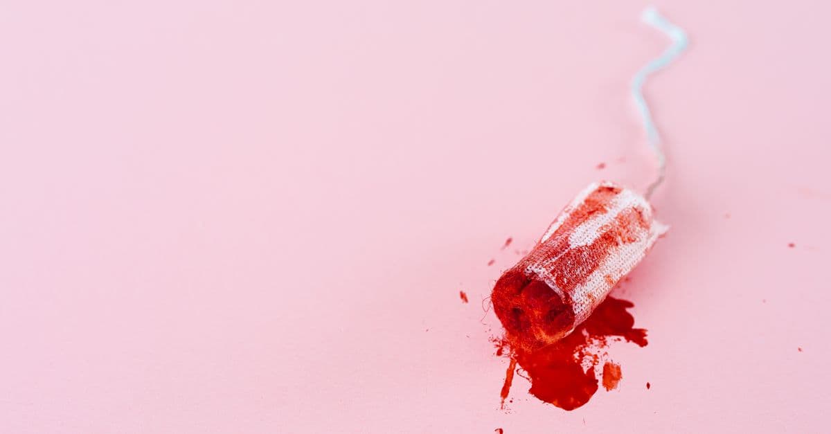 Detailed image of a menstrual tampon with blood stains on a pink background, highlighting menstruation and menstrual hygiene.